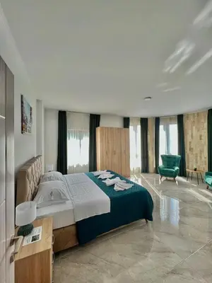a bedroom with a large bed and a green chair at Mir i More in Dobra Voda