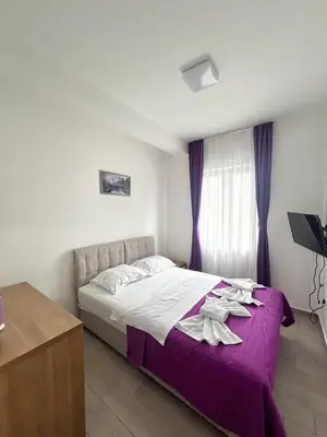 a bedroom with a bed with purple sheets and a window at Mir i More in Dobra Voda