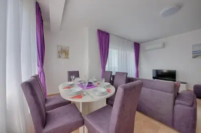 a dining room with a table and purple chairs at Mir i More in Dobra Voda