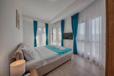 a bedroom with a bed with blue drapes at Mir i More in Dobra Voda