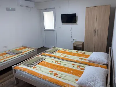 a room with two beds and a tv on the wall at Njaro del Mar Zukovica 2 in Žukovica
