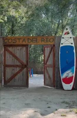 a surfboard leaning against a wooden gate with a door with a sign at Costa Del Rio in Bistrice