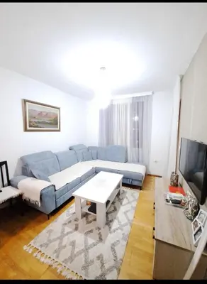 a living room with a blue couch and a tv at Apartman Podgorica - Pobrezje in Podgorica