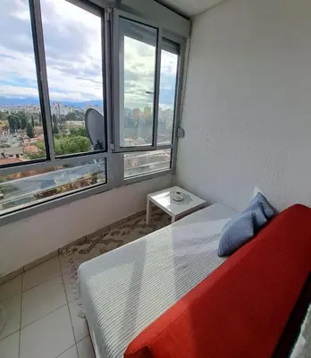 a bedroom with a bed with a red blanket and two windows at Apartman Podgorica - Pobrezje in Podgorica