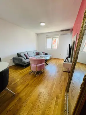 a living room with a couch and a table and a mirror at Royal Stay Podgorica - Princess Apartment in Podgorica