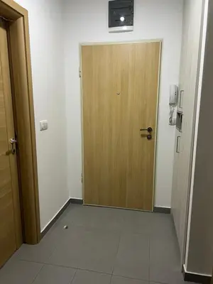 a hallway with a wooden door and a tile floor at Royal Stay Podgorica - Princess Apartment in Podgorica