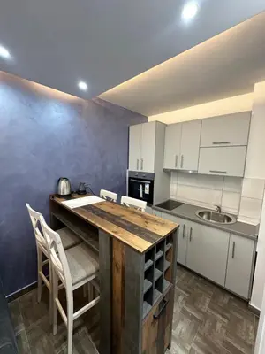 a kitchen with a wooden table and white cabinets at Etihad Apartments&Spa in Ulcinj