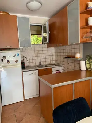 a kitchen with wooden cabinets and a white refrigerator at Appartement centre avec garage privé in Budva