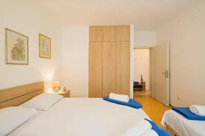 a bedroom with two white beds and a wooden closet at Apartment Srdanovic in Budva