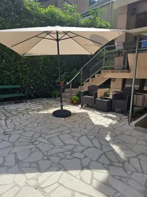 an umbrella on a patio with chairs and stairs at Apartment Srdanovic in Budva