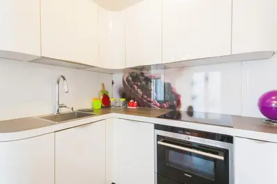 a kitchen with white cabinets and a black oven at Apartment Mia in Sveti Stefan