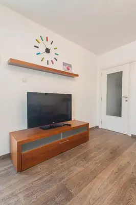 a living room with a tv and a clock on the wall at Apartment Mia in Sveti Stefan