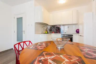 a kitchen with a wooden table and white cabinets at Apartment Mia in Sveti Stefan