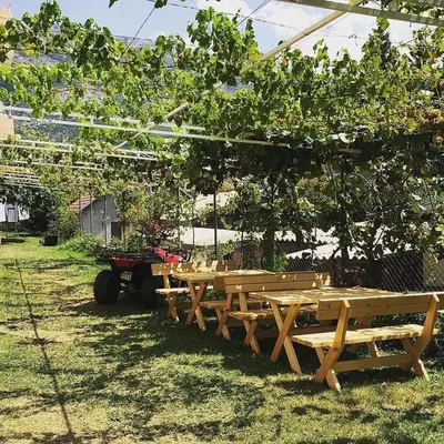 a group of wooden tables under a canopy in a yard at Apartments Music in Sutomore