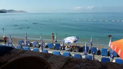 a beach with chairs and people in the water at Apartments Music in Sutomore