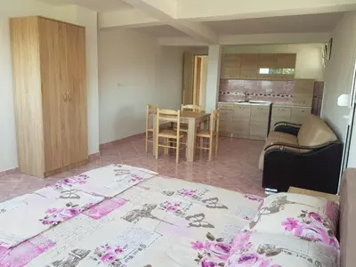 a bedroom with a bed and a kitchen with a table at Guest House Dragomir in Sutomore