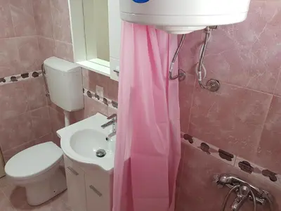 a bathroom with a pink shower curtain and a sink at Guest House Dragomir in Sutomore