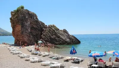 a beach with a bunch of chairs and umbrellas at Apartments Milos Kaladjurdjevic in Budva