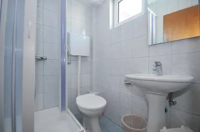 a white bathroom with a toilet and a sink at Apartments Milos Kaladjurdjevic in Budva
