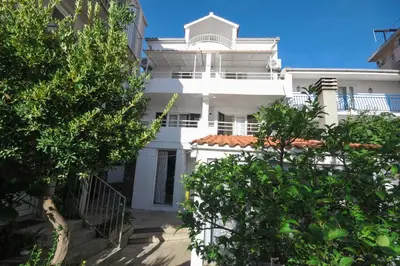 a white building with trees in front of it at Apartments Milos Kaladjurdjevic in Budva