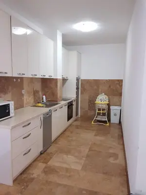 an empty kitchen with white cabinets and a table in it at Luxury Apartments Trend in Budva