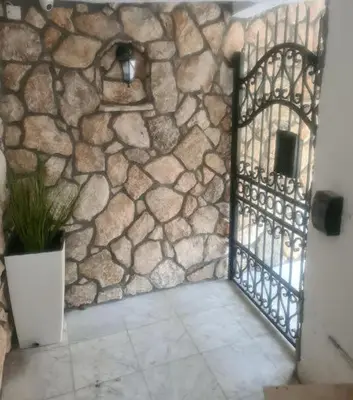 a stone wall with a gate and a potted plant at Malibu Apartments in Sutomore