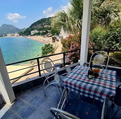 a table and chairs on a balcony with a view of the beach at Malibu Apartments in Sutomore
