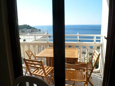 a table and chairs on a balcony with the ocean at Milocer Apartment in Sveti Stefan