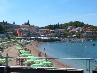a beach with umbrellas and people in the water at Milocer Apartment in Sveti Stefan