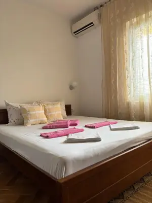 a bed with white sheets and pink towels on it at Apartments Old Olive in Bar
