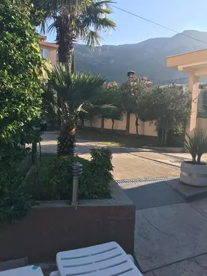 a park with two white benches and palm trees at Vila Laguna in Sutomore