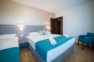 a hotel room with two beds and a chair at Guest House S-Lux in Petrovac na Moru