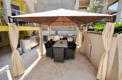 a patio with a table and chairs under an umbrella at Villa Medusa Apartments - Adults only - in Dobra Voda