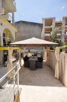 a patio with a large umbrella and tables and chairs at Villa Medusa Apartments - Adults only - in Dobra Voda