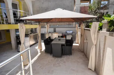 a kitchen with a table and a large umbrella at Villa Medusa Apartments - Adults only - in Dobra Voda
