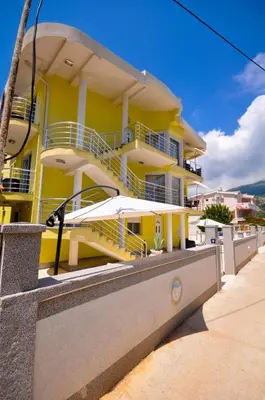 a yellow building with white balconies on a sidewalk at Villa Medusa Apartments - Adults only - in Dobra Voda