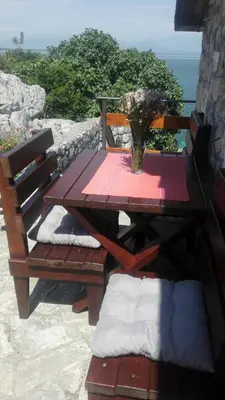 a wooden table and bench with a vase of flowers on it at Holiday home Raduš in Virpazar