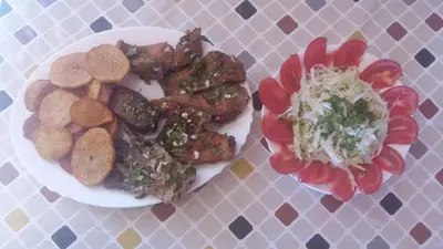 a plate of food with meat and vegetables on a table at Holiday home Raduš in Virpazar