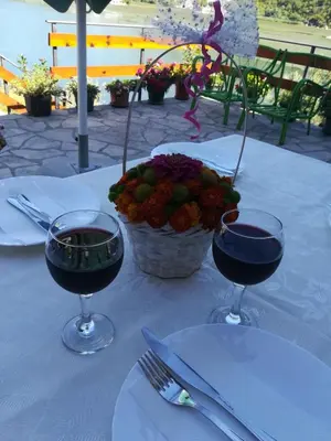 a table with two glasses of wine and a basket of flowers at Holiday home Raduš in Virpazar