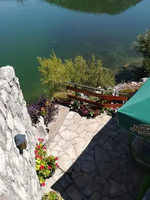 a stone retaining wall with a bench and flowers at Holiday home Raduš in Virpazar