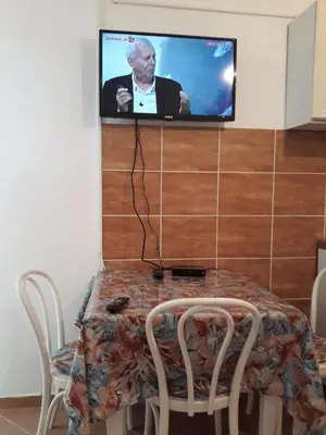 a table with chairs and a tv on a wall at Apartments Jovanic with 2 bedrooms in Sutomore