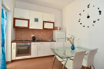 a kitchen with a glass table and white cabinets at Blue Mare Apartment in Petrovac na Moru