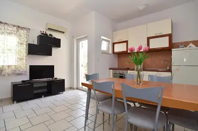 a kitchen with a table and chairs and a refrigerator at Blue Mare Apartment in Petrovac na Moru