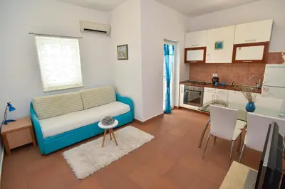 a living room with a blue couch and a kitchen at Blue Mare Apartment in Petrovac na Moru