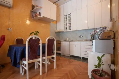 a kitchen with a table and white cabinets at Apartment Mira in Budva