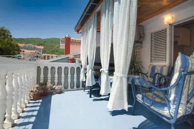 a balcony with chairs and curtains on a house at Apartment Mira in Budva