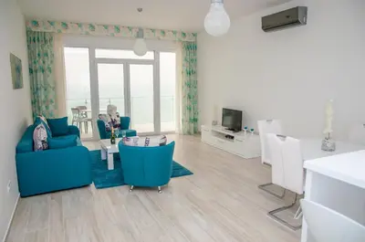 a living room with blue chairs and a table and a tv at Nautilus Apartments in Dobra Voda