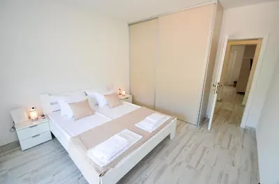 a white bedroom with a large white bed with pillows at Bay View Apartments in Kotor