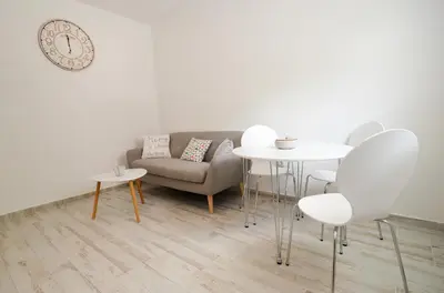 a living room with a couch and tables and a clock at Bay View Apartments in Kotor