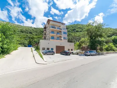 a building on the side of a road with parked cars at Welcome Apartments in Petrovac na Moru